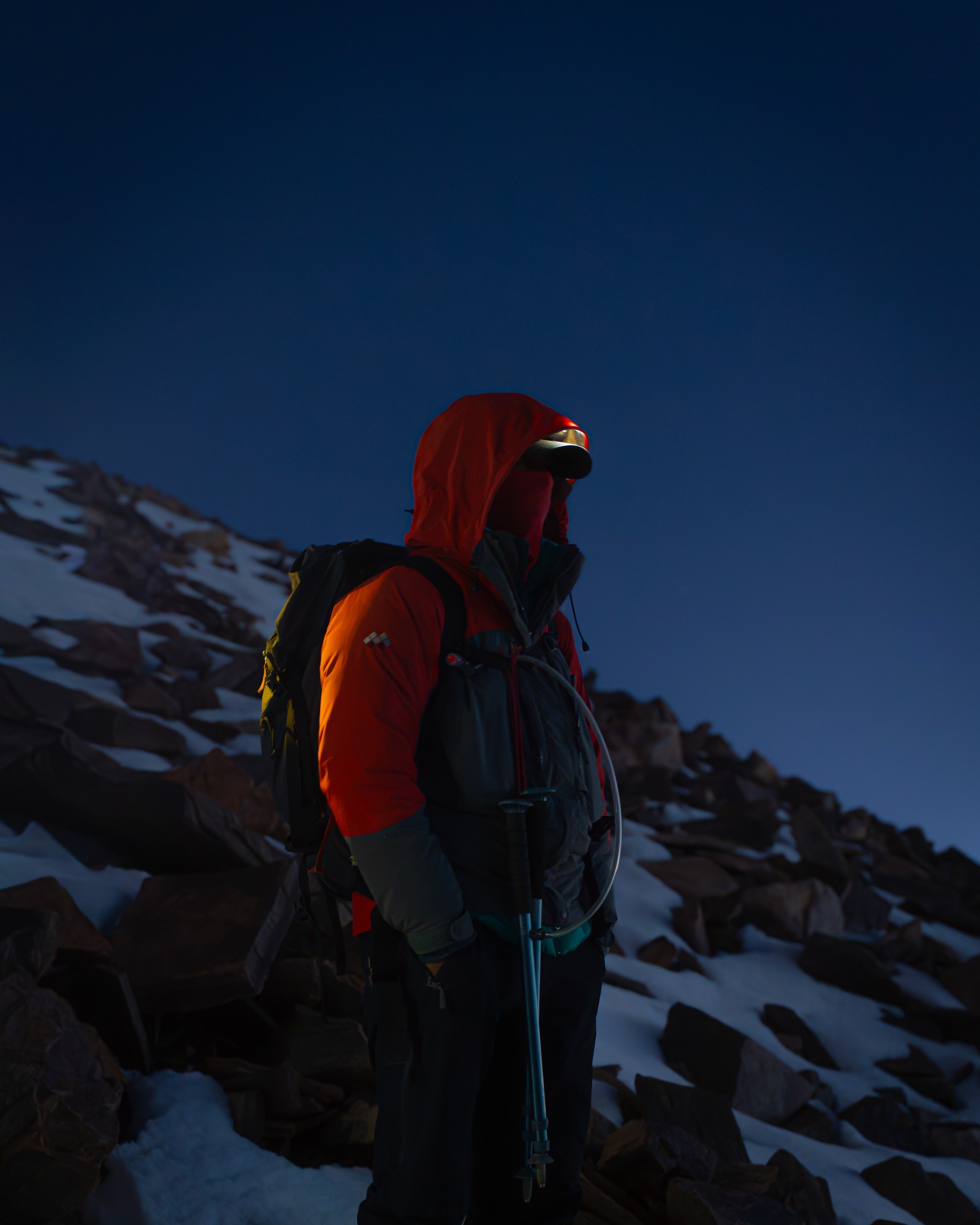 A climber in red standing in blue-hour mountain light