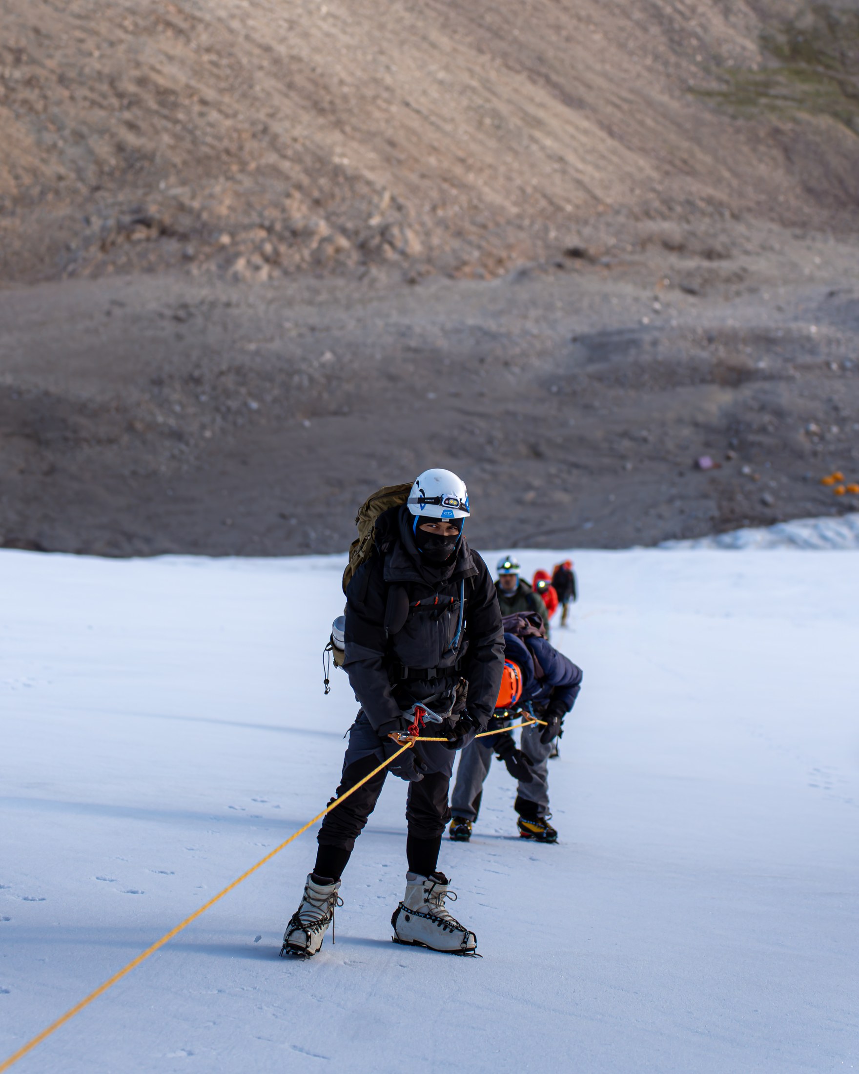 A rope team ascends the snowy slope on Kaigar Ri