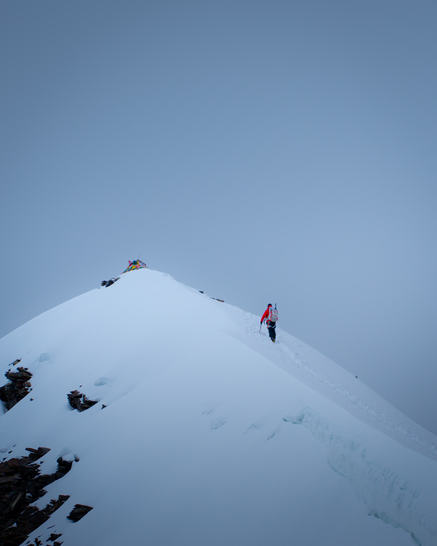 A small climber on a sweeping snow ridge on Kang Yatse II