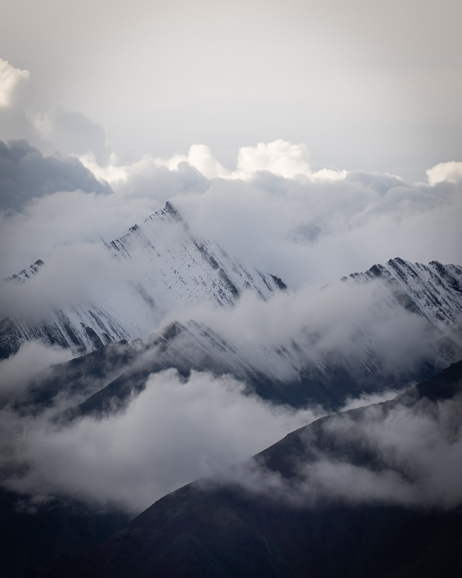 Snow-covered mountain ridges emerge through clouds on the Kang Yatse II expedition