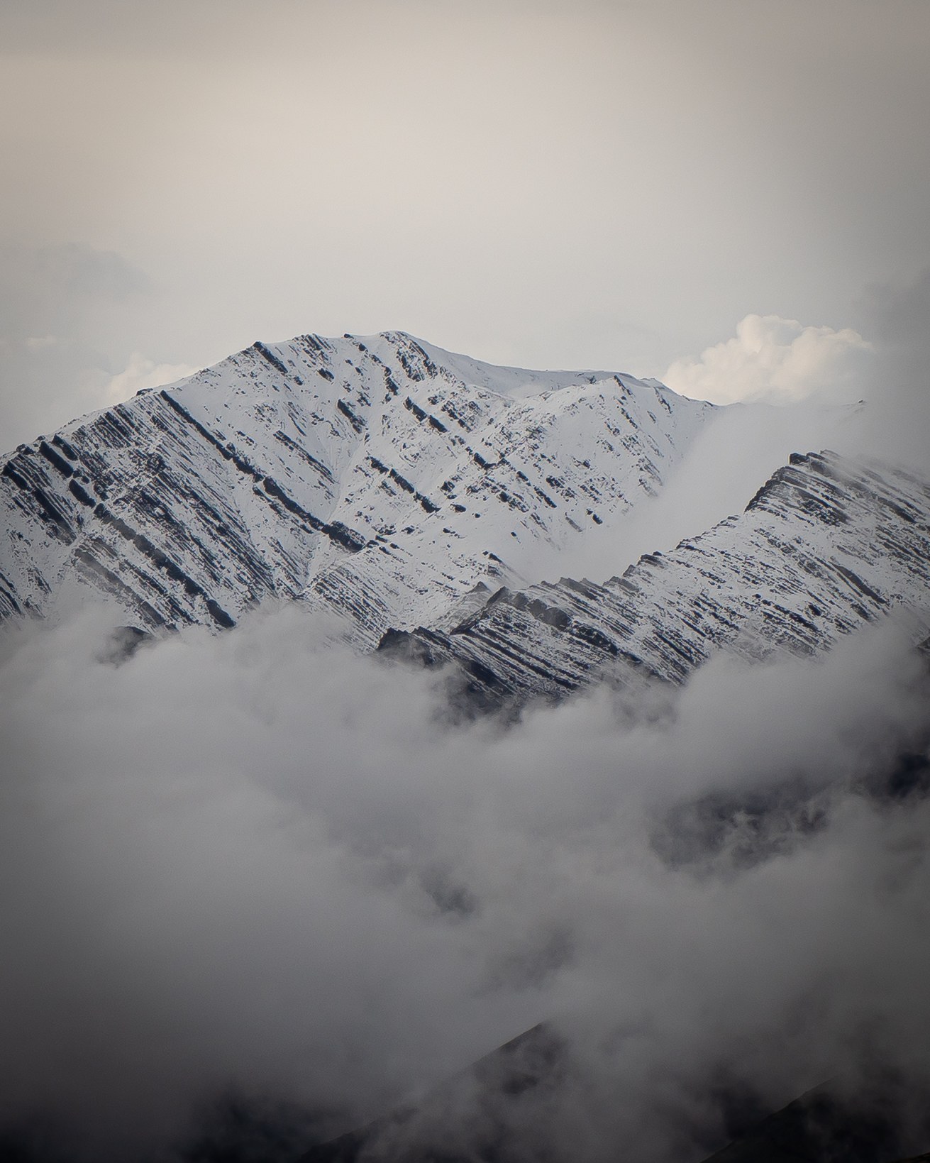 A sharply defined snowy mountain ridge surrounded by low cloud